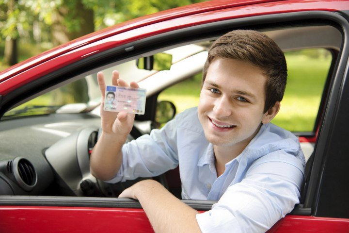 парень в машине держит водительские права